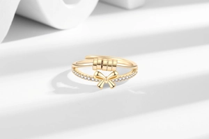 Detail of spinning beads and crystal bow on rotatable anxiety ring in gold finish