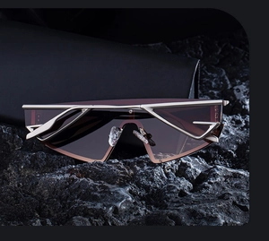 Detail of champagne gold metal cut-out frame sun glasses on black volcanic rock background