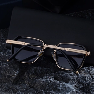Lunettes de soleil carrées luxe noir et or avec branches en métal vintage sur pierre