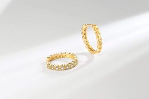 Vue macro de boucles d'oreilles créoles dorées avec zircons blancs et bords ondulés