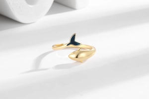 Macro view of adjustable mermaid tail ring featuring glittering blue enamel on gold metal
