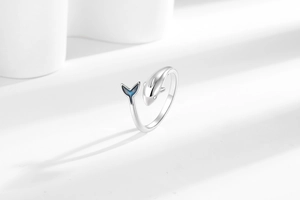 Macro detail of silver dolphin ring featuring blue enamel tail on white display