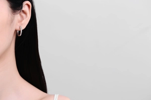 Macro detail of silver hoop earring featuring fine pave-set cubic zirconia on female model