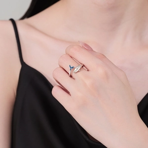Minimalist silver dolphin wrap ring featuring blue enamel fishtail on a female finger