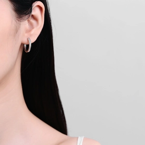 Elegant silver hoop earrings with clear crystals shown on ear for a minimalist look