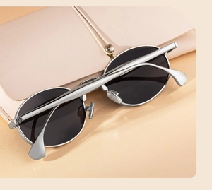 Retro oval sunglasses with silver metal frame and dark lenses on a pink leather case