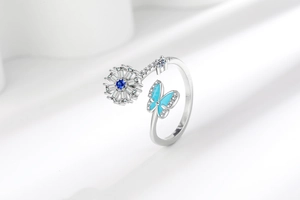 Macro shot of silver rotating ring featuring a blue enamel butterfly and crystal flower
