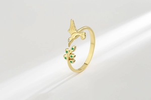 Vue détaillée d'une bague colibri avec pierres vertes et jeux d'ombre diagonaux
