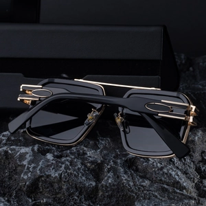Detail of square sunglasses with gold metal bridge and black textured leather case