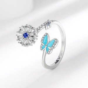 Adjustable spinner ring with blue butterfly and floral gemstone on silver band