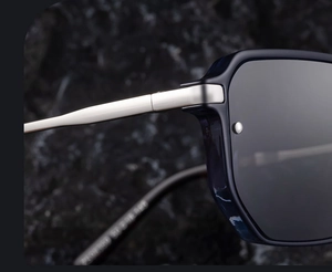 Detail of matte silver metal hinge and temple of polarized sunglasses on a rock