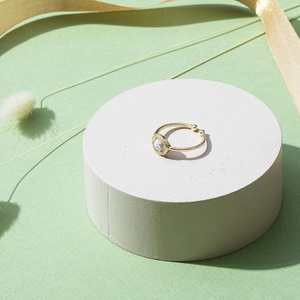 Adjustable gold opal ring with sparkling halo setting on a light green gift background