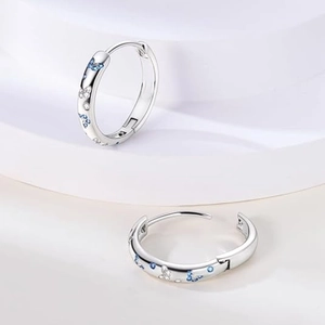 Créoles en argent avec motifs papillon et zircons bleus sur des marches blanches