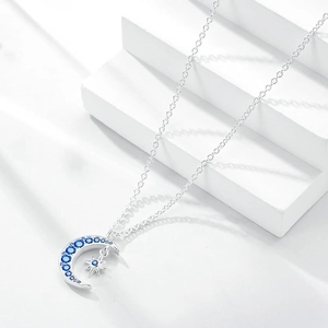 Collier lune et étoile en argent avec zircons bleu foncé sur présentoir blanc