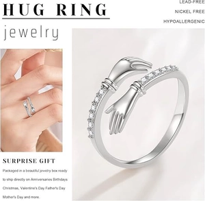 Macro shot of silver-tone hug ring featuring crystal pavé hands on a model hand
