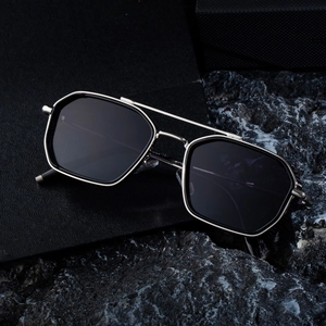 Modern silver geometric sunglasses with double bridge and dark lenses on a textured background