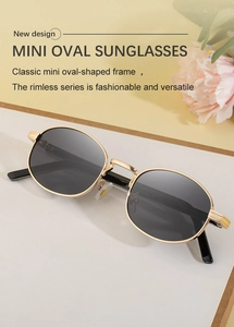 Detail of oval metal sunglasses with golden frame and dark lenses on a floral background