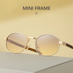 Detail of mini oval metal sunglasses with golden frame and gradient brown lenses