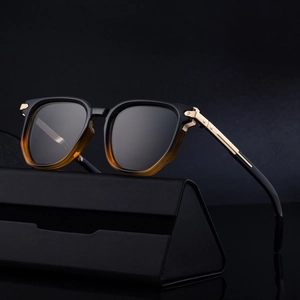 Polygonal sunglasses with black and amber frames, gold metal temples, and a black leather case