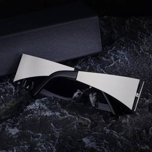 Detail of square shield sunglasses with silver metal frame on dark volcanic rock