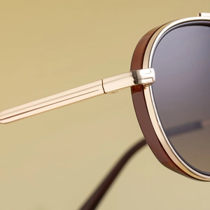 Macro detail of golden metal hinges and brown acetate frame on oval punk sunglasses