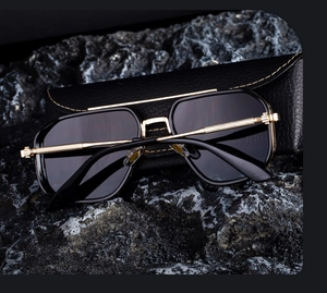 Détail de lunettes aviateur carrées avec monture dorée et étui en cuir noir