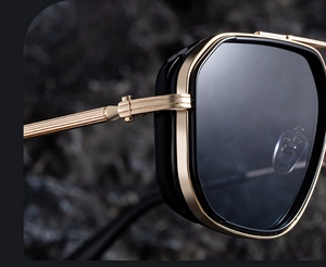 Macro des charnières dorées texturées et protections latérales noires sur lunettes de soleil