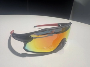 Detail of sports cycling sunglasses with rainbow tinted lens and red black frame