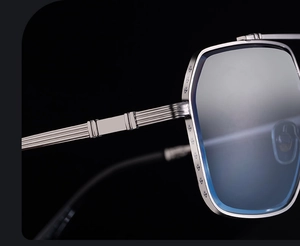 Macro shot of silver metal sunglasses frame with engraved floral pattern and blue lenses