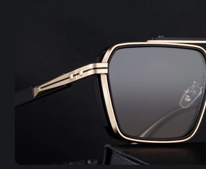 Macro view of square frame sunglasses with golden honeycomb metal hinge and black trim