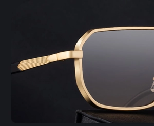 Close-up of golden metal frame with textured hinge and dark grey lenses on square sunglasses