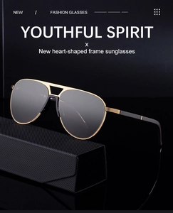 Detail of retro aviator sunglasses with gold metal frame resting on a black leather case