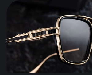 Detail of square sunglasses featuring golden metal temples with intricate hollow carvings