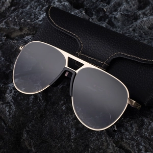 Classic aviator sunglasses with gold metal frame and dark lenses on a textured rock base