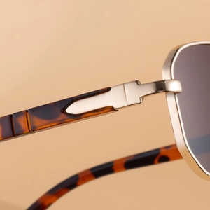 Detail of golden metal hinge and tortoise shell temple on square frame sunglasses