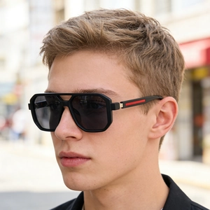 Détail de lunettes de soleil carrées noir mat avec rayures rouges sur la branche latérale