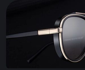 Close-up of black and gold pilot sunglasses featuring reinforced metal hinge details