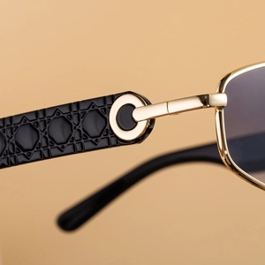 Detailed macro view of black cannage quilted temples and golden hollow-out hinges of sunglasses