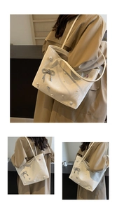 Close-up of cream tote bag featuring pearl embellishments and a silver bow charm