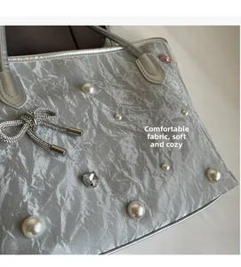 Macro detail of silver crinkled tote bag featuring pearls, crystals and a diamond bow