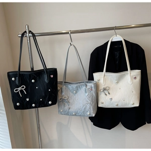 Detailed view of three metallic tote bags with pearl and bow charms in black, silver, and white