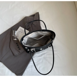 Detail view of large capacity black tote bag interior with pearl bow charm and inner pockets