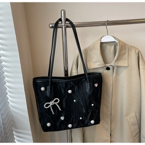 Detail of black tote bag with white pearls, silver diamond bow, and heart charms