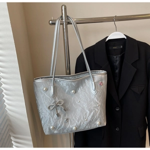 Detailed shot of a silver tote bag with pearl accents and a crystal bow decoration