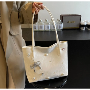 Detail of white tote bag with pleated texture, faux pearls and rhinestone bow decoration
