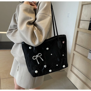 Detail of black tote bag featuring delicate pearl embellishments and a silver bow