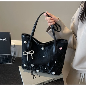 Detail of black pleated tote bag featuring pearls, rhinestone bow, and pink heart gem