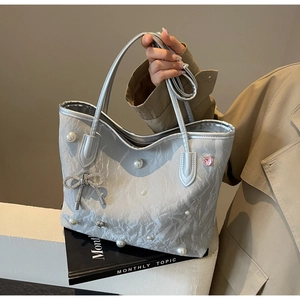 Detail of silver tote bag with pearl rivets, metal bow and pink heart crystal decoration