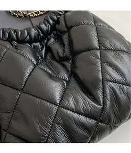 Close-up of black quilted puffer tote fabric with elegant gold chain shoulder strap