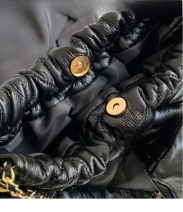 Close-up of golden magnetic closure and textured black crinkled leather on shoulder bag